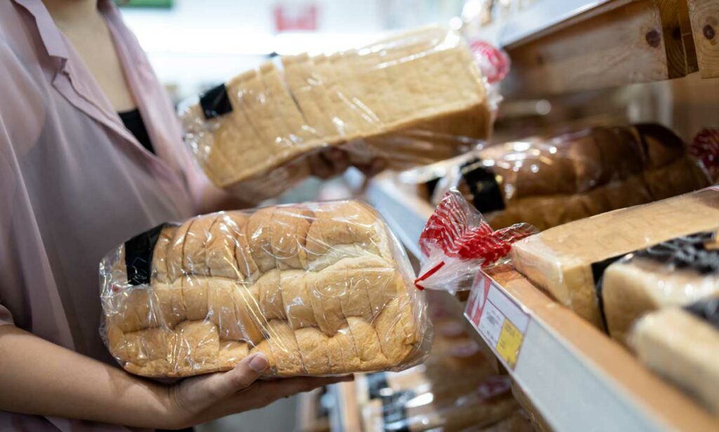 Consumer Choosing Premium Bread Options At Supermarket